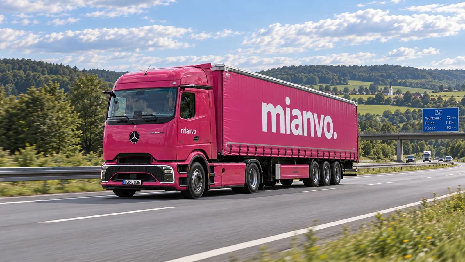 Pinker mianvo eActros 600 mit Planenauflieger auf einer Autobahn zwischen grünen Hügeln