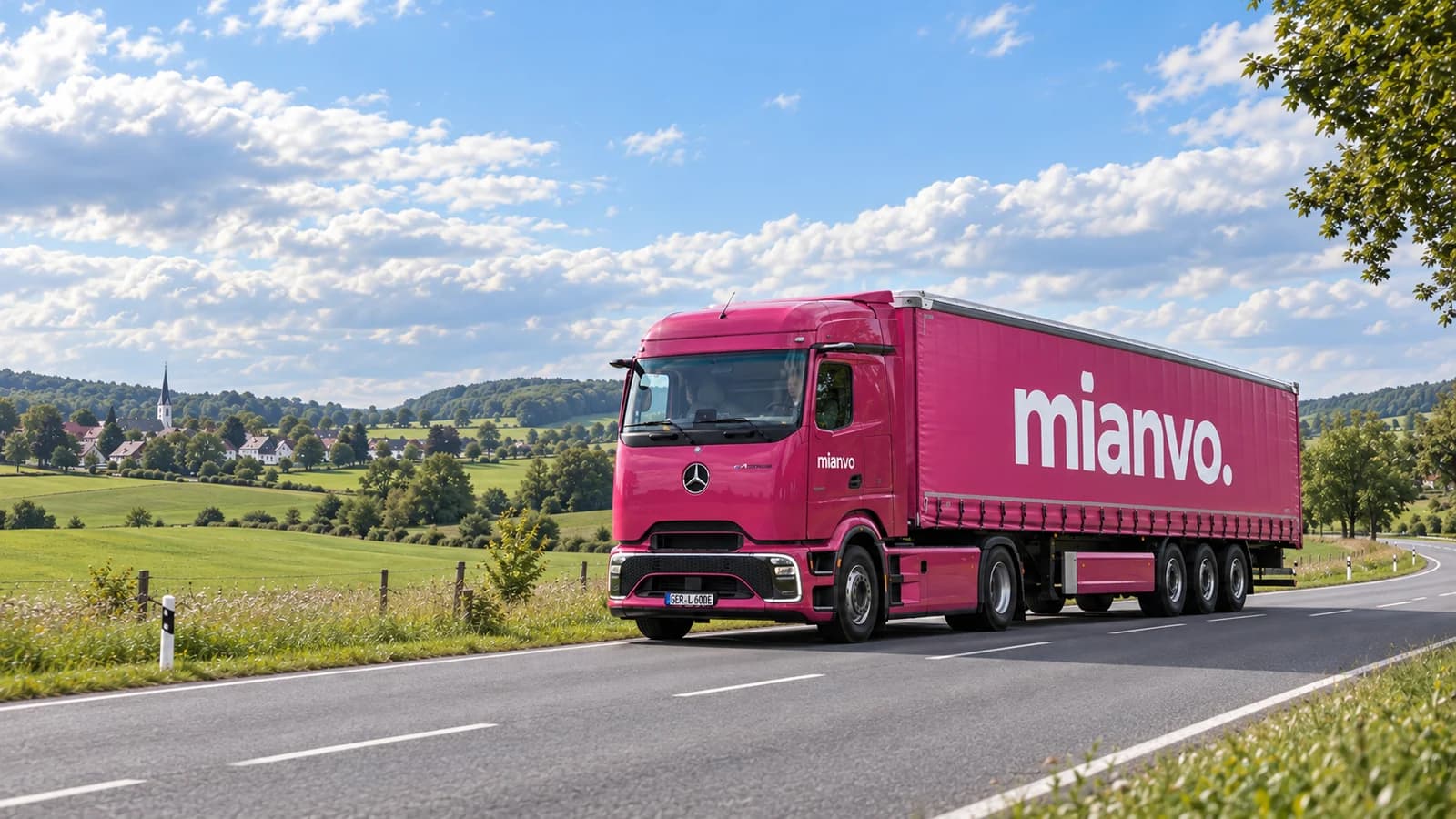 Pinker Mercedes-Benz eActros 600 ProCabin mit mittigem mianvo.-Schriftzug auf dem Planenauflieger in grüner Landschaft